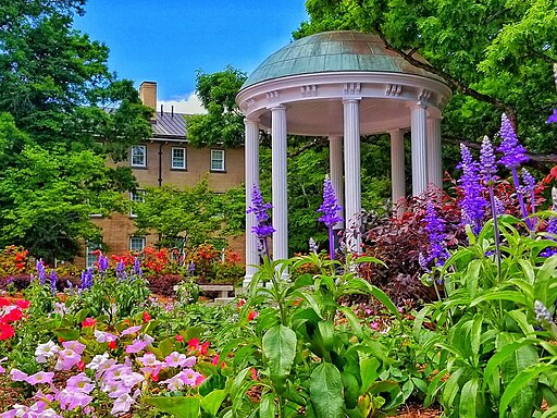 campus brick building in background with old well and spring flowers blooming in foreground