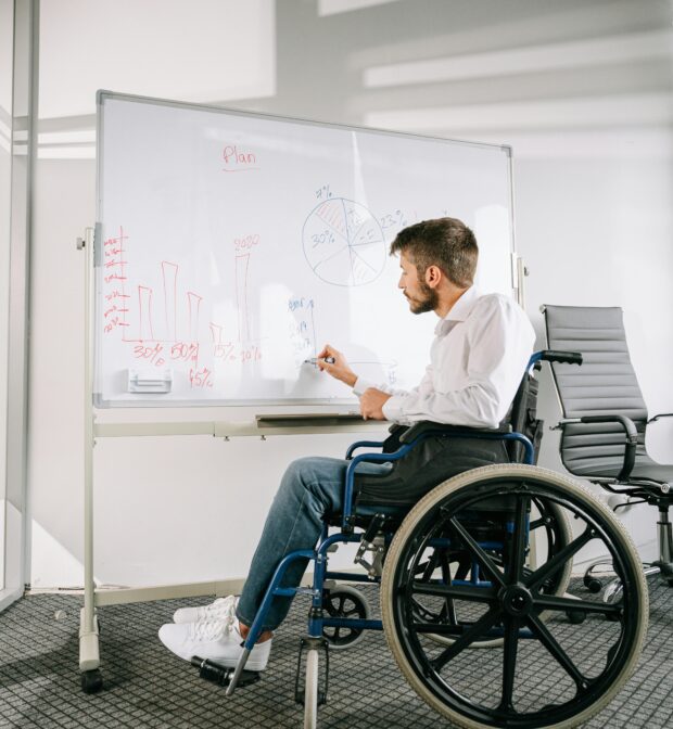 young man in wheelchair writing on a whiteboard