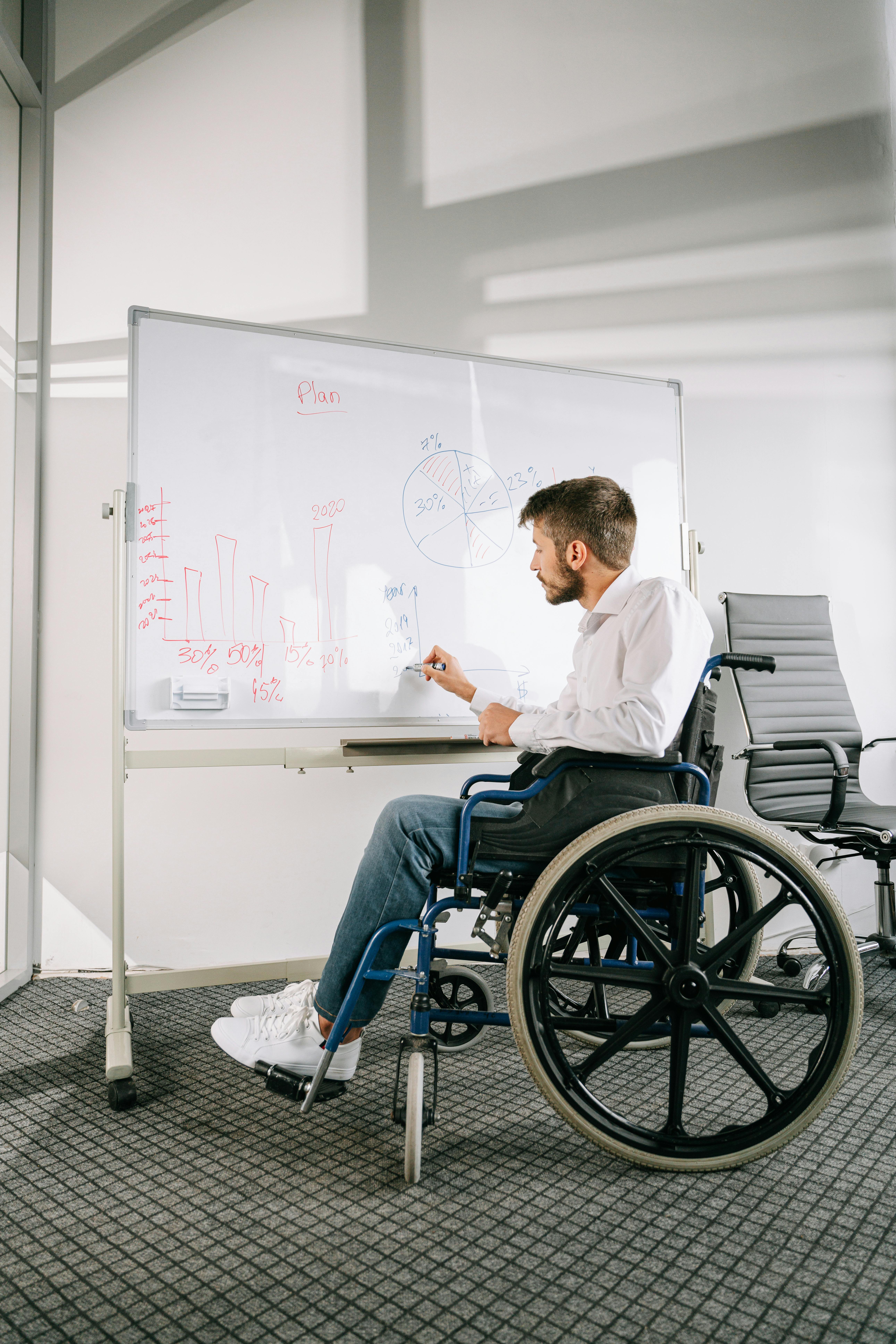 young man in wheelchair writing on a whiteboard