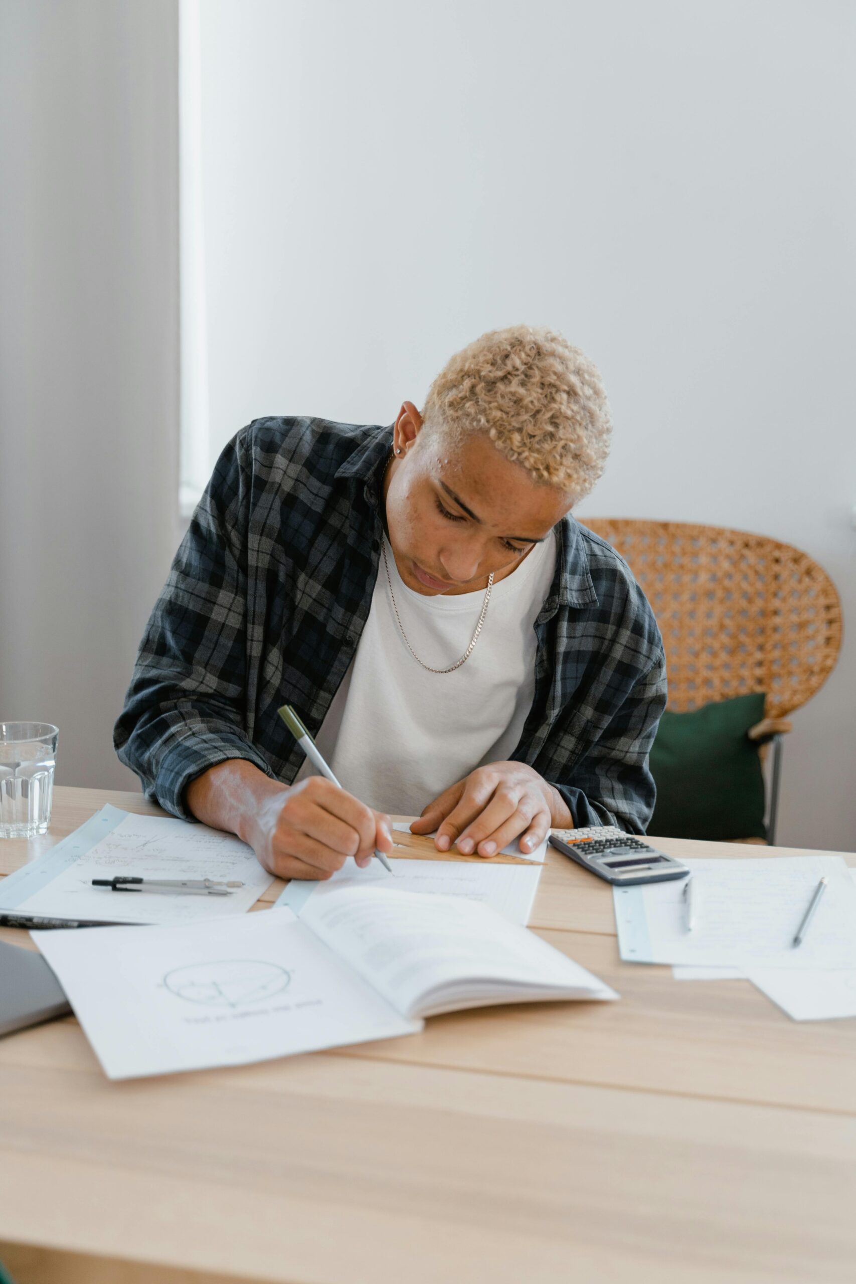 young man writing at a desk with various papers in front of him