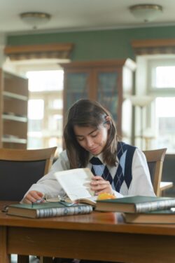 young woman in argyle vest sitting at desk studying