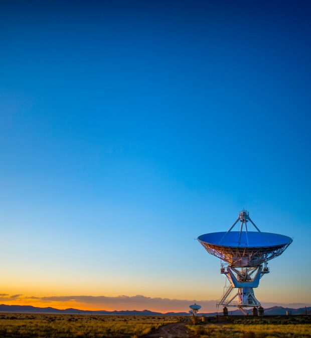 Large grey satellite disc in field at sunrise