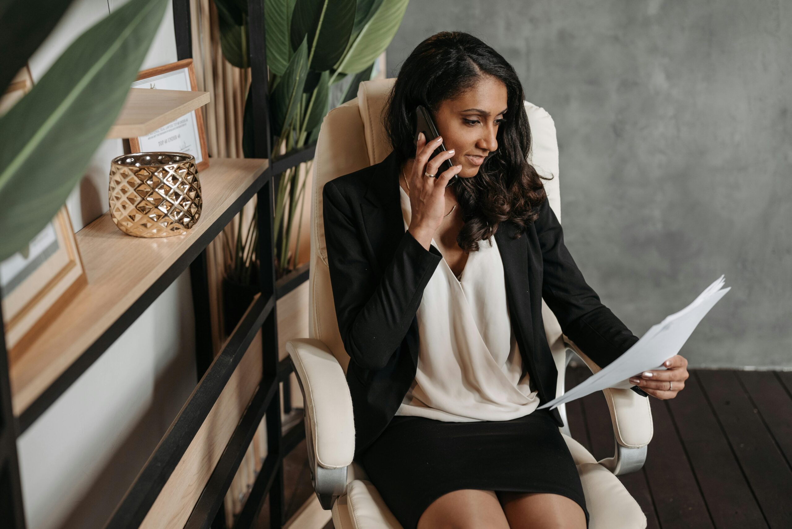 Business woman sitting down, on phone, looking at paper