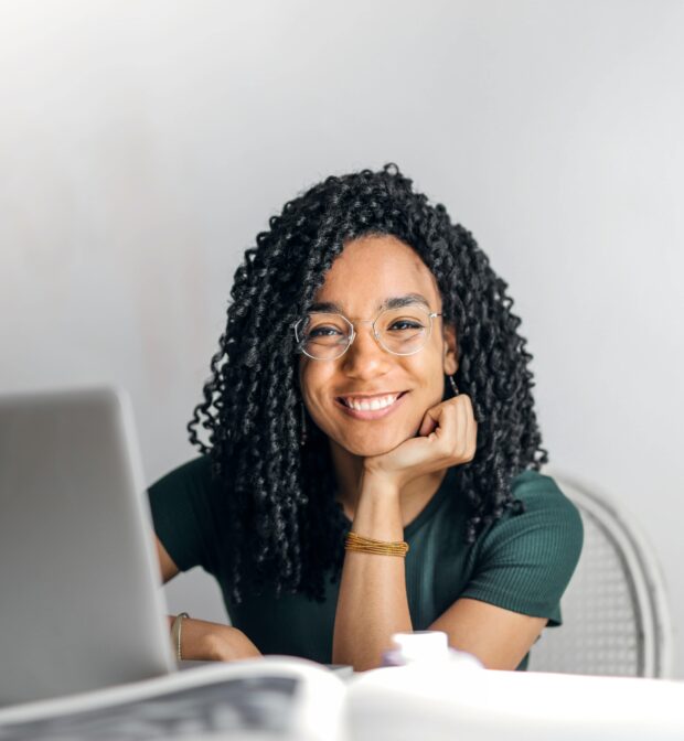 student working on laptop, smiling at camera