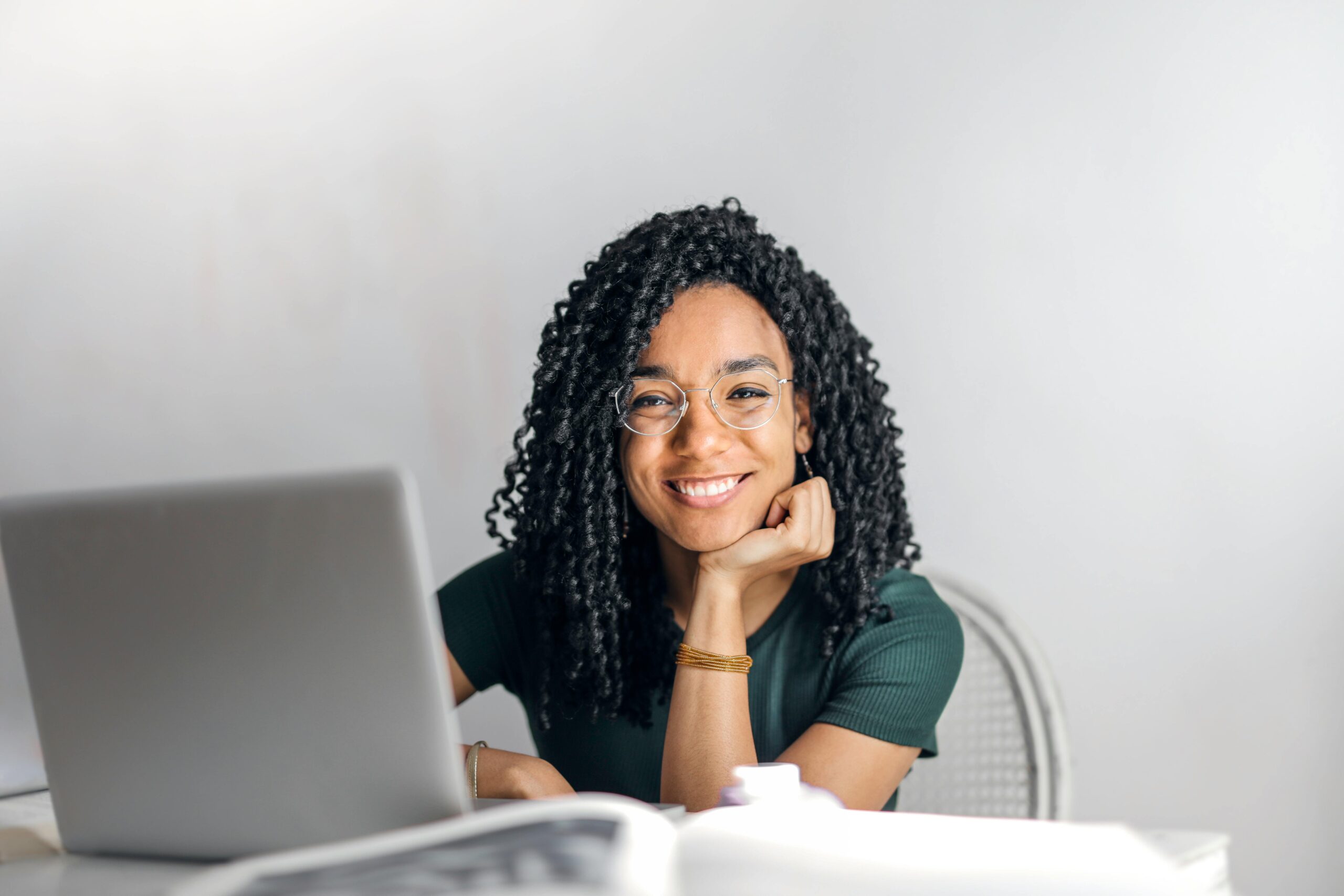 student working on laptop, smiling at camera