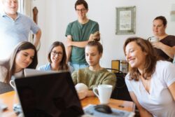 Group of people sitting around a laptop intently