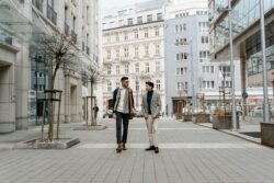 two men dressed in business clothing walking down street in city