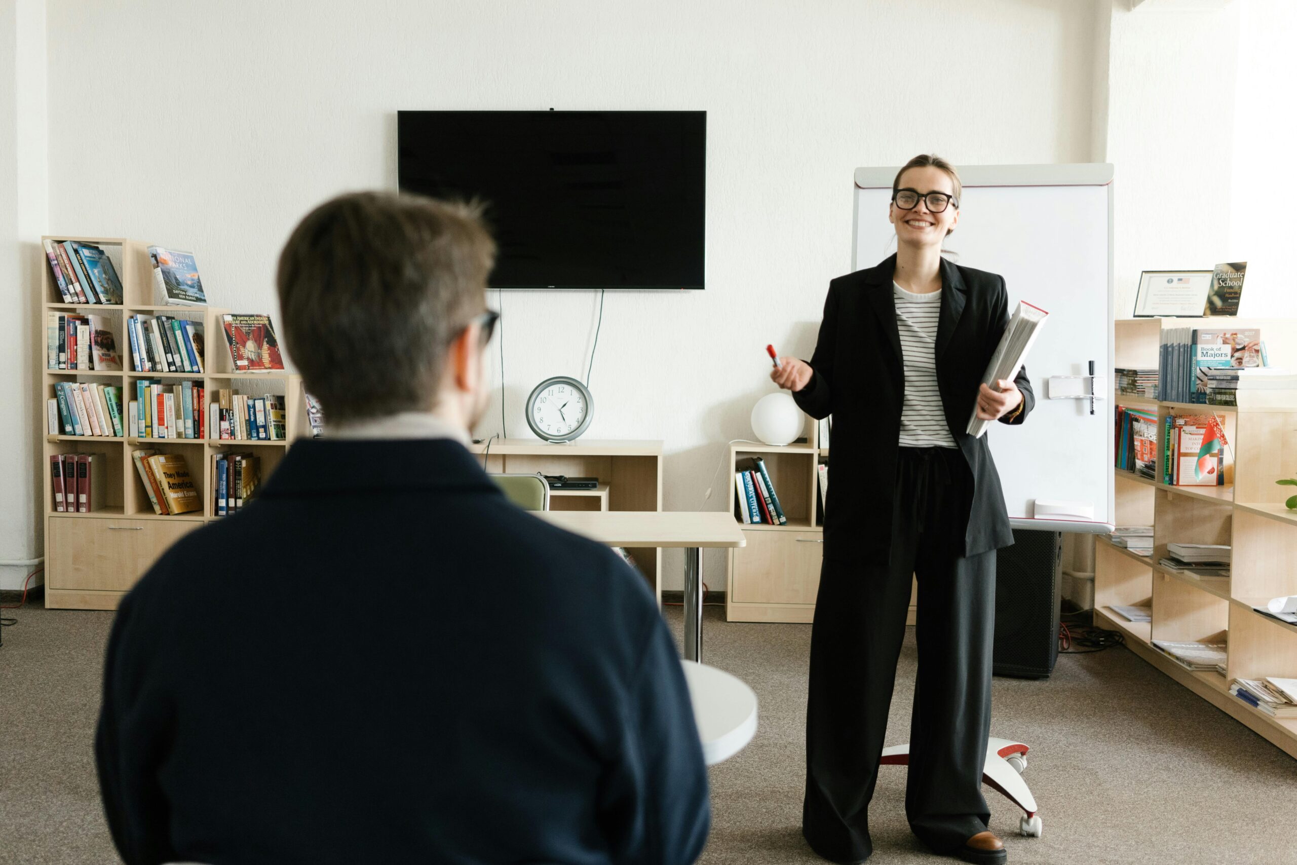 Woman in business attire talking to man in business attire with his back turned to camera