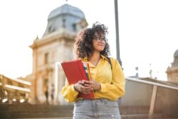 Girl standing near tall building holding books