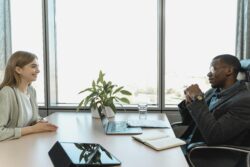 two people in business attire having conversation on either side of a desk