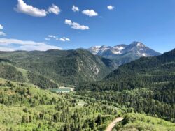 Landscape image of Provo Utah wilderness featuring forest, mountains, and small lake in distance