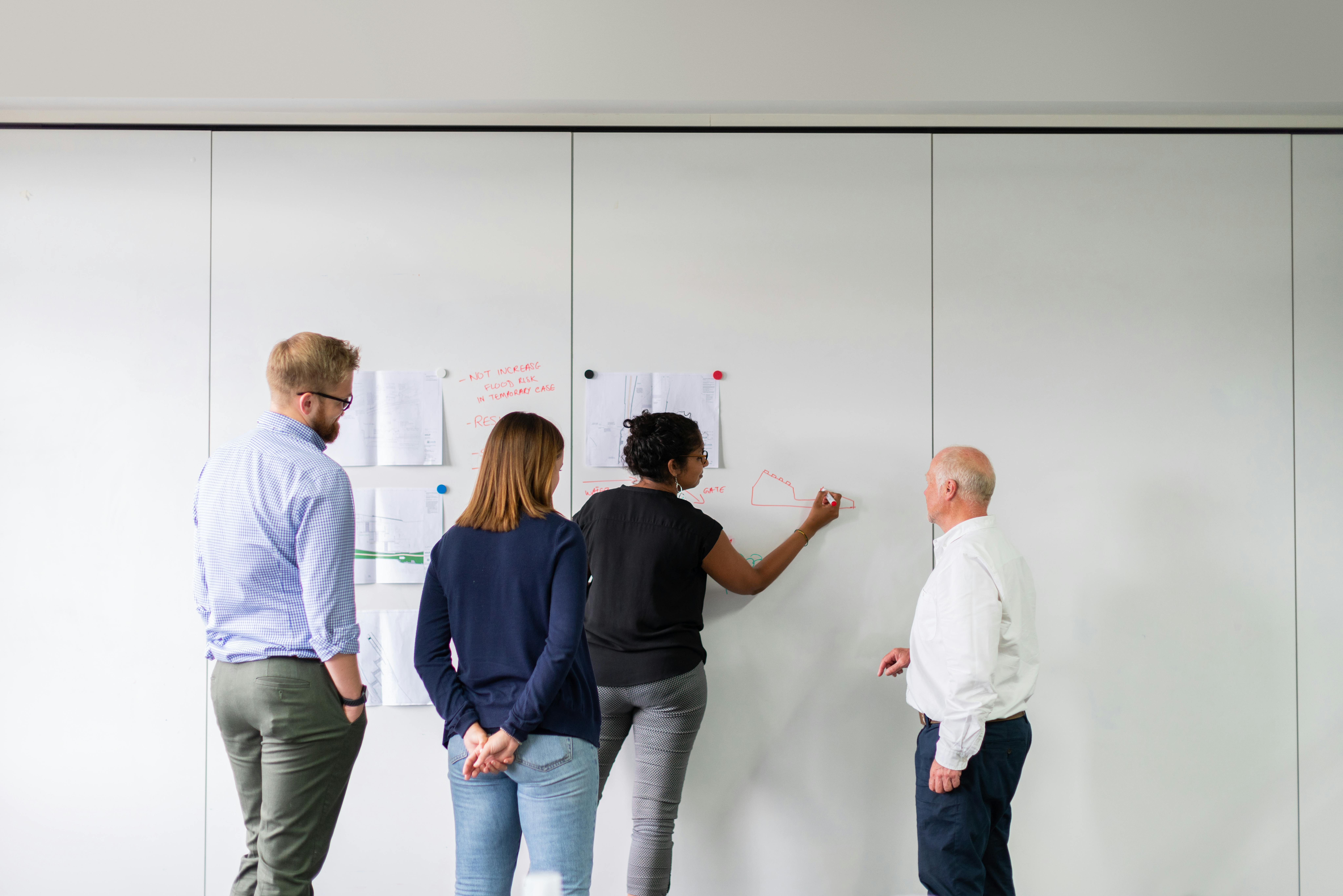 Group of people in business casual attire writing notes and pinning them to the wall