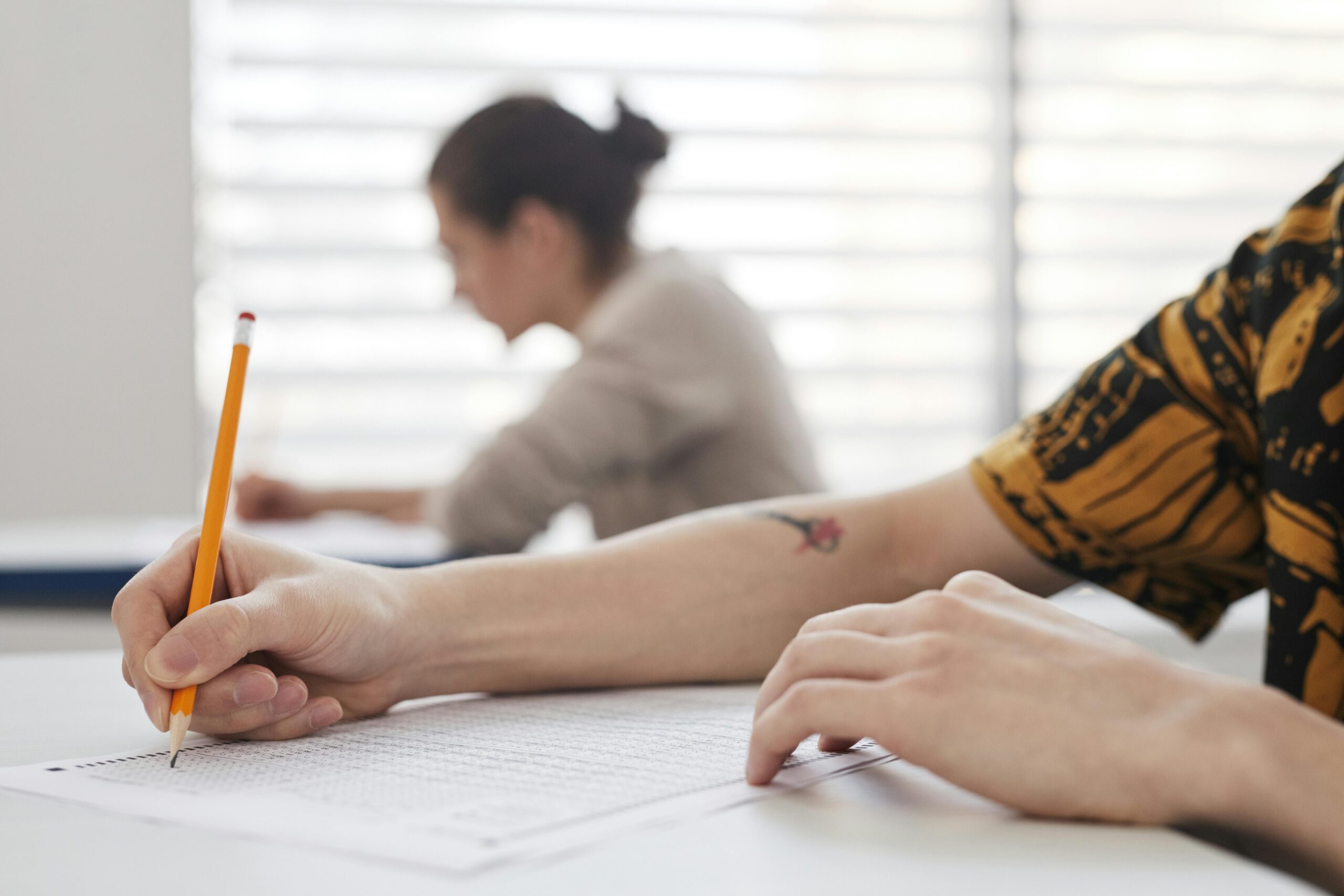 A Person Writing on a Paper Using Pencil