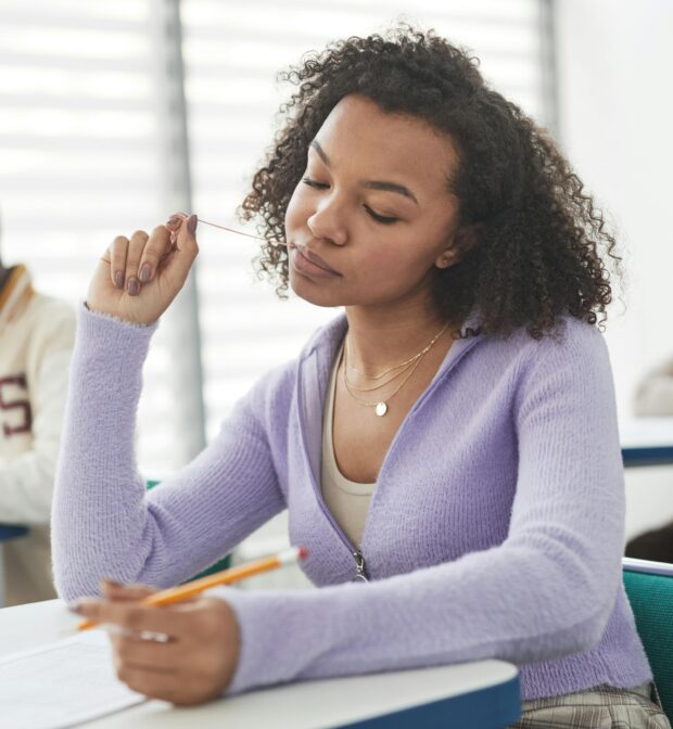 Close-Up Photo of a Woman in a Purple Cardigan Sweater Taking an Exam