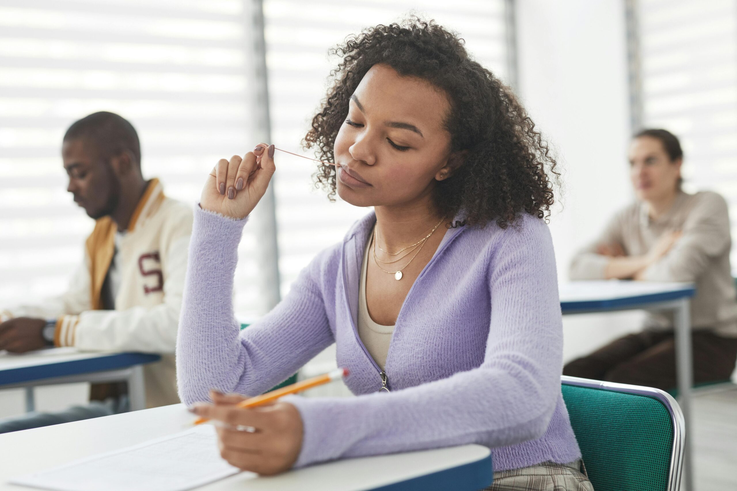 Close-Up Photo of a Woman in a Purple Cardigan Sweater Taking an Exam