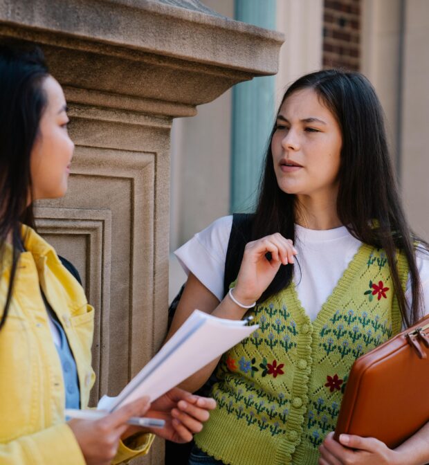 Woman in a Green Sweater Vest Talking with Her Friend