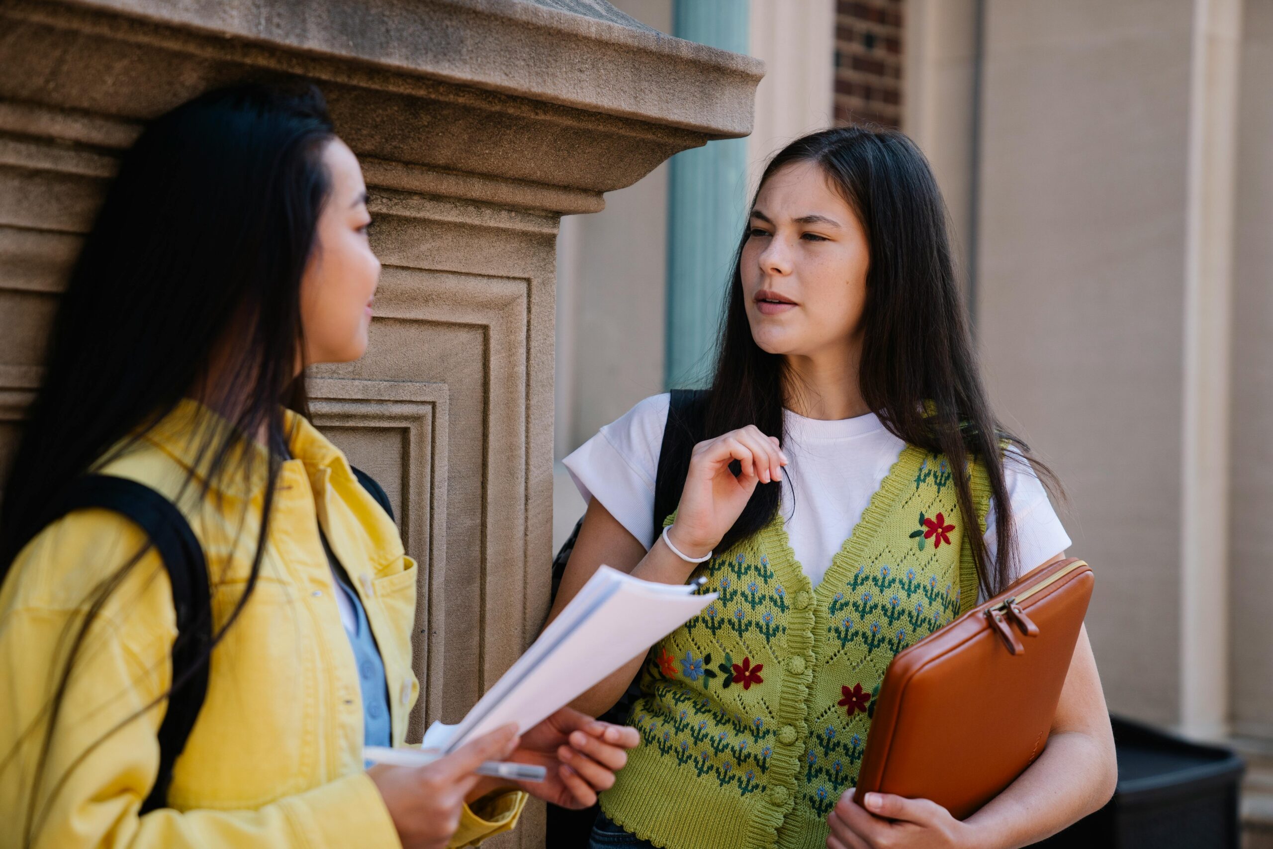 Woman in a Green Sweater Vest Talking with Her Friend