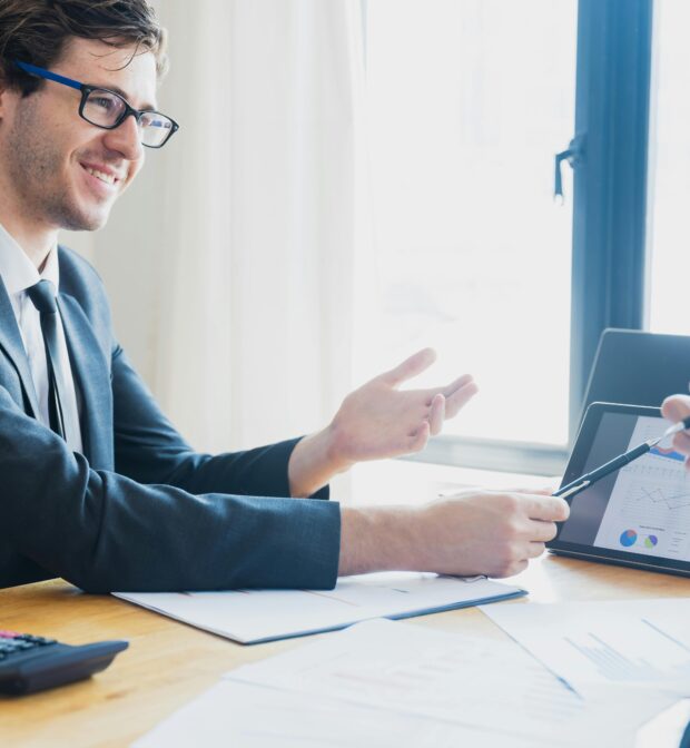 A Man in Black Suit Presenting Using a Tablet Device
