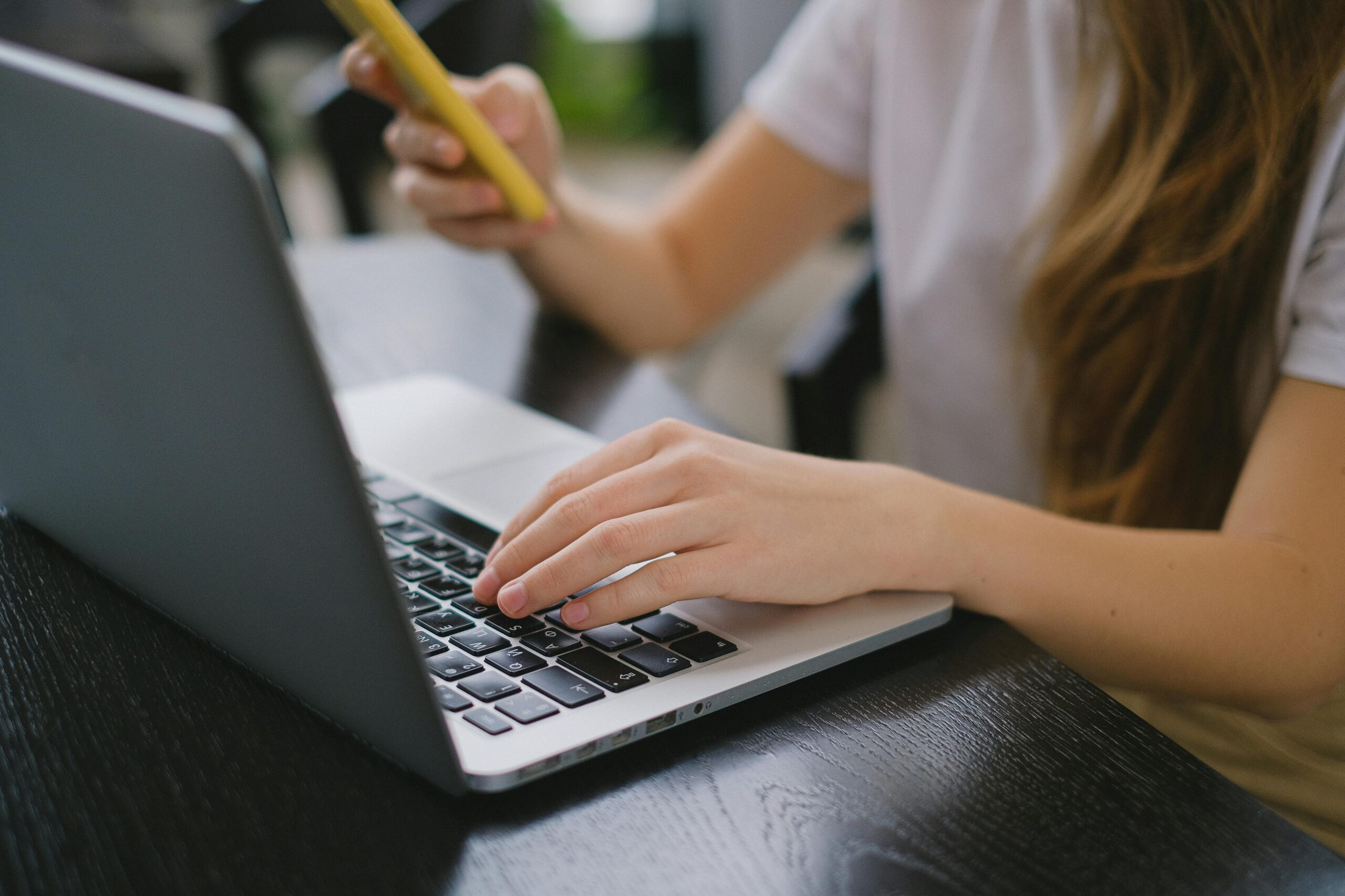 A Person in White Shirt Using a Laptop